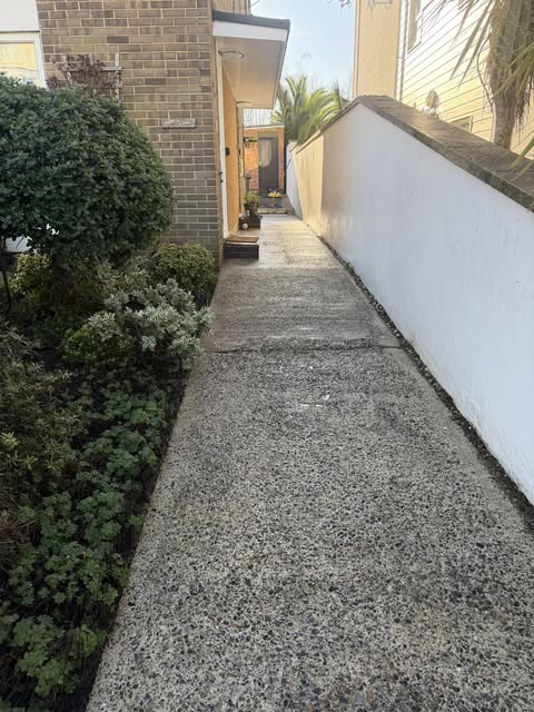 Clean narrow side pathway between brick and white wall
