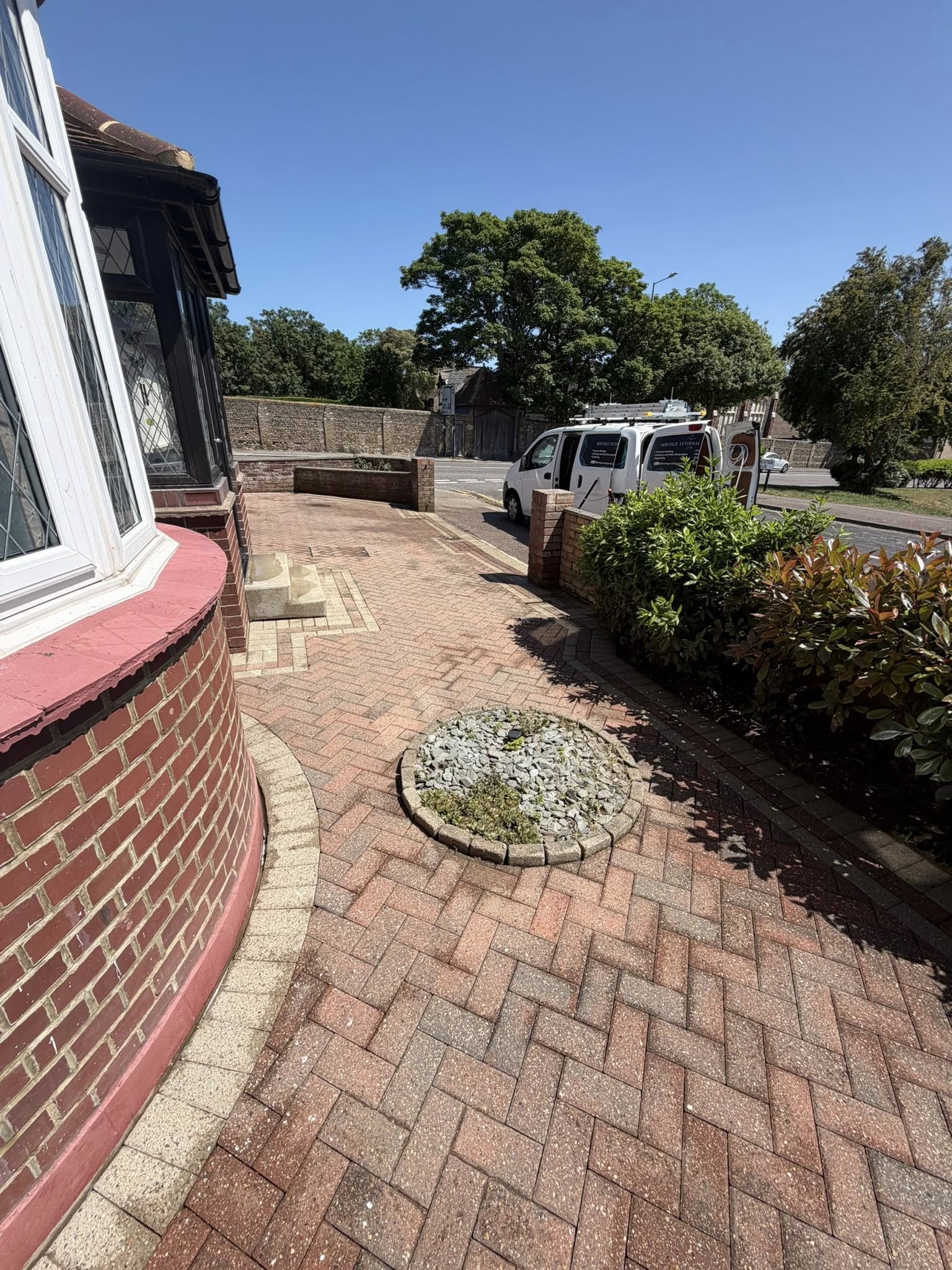 Clean driveway and patio with landscaping and parked van