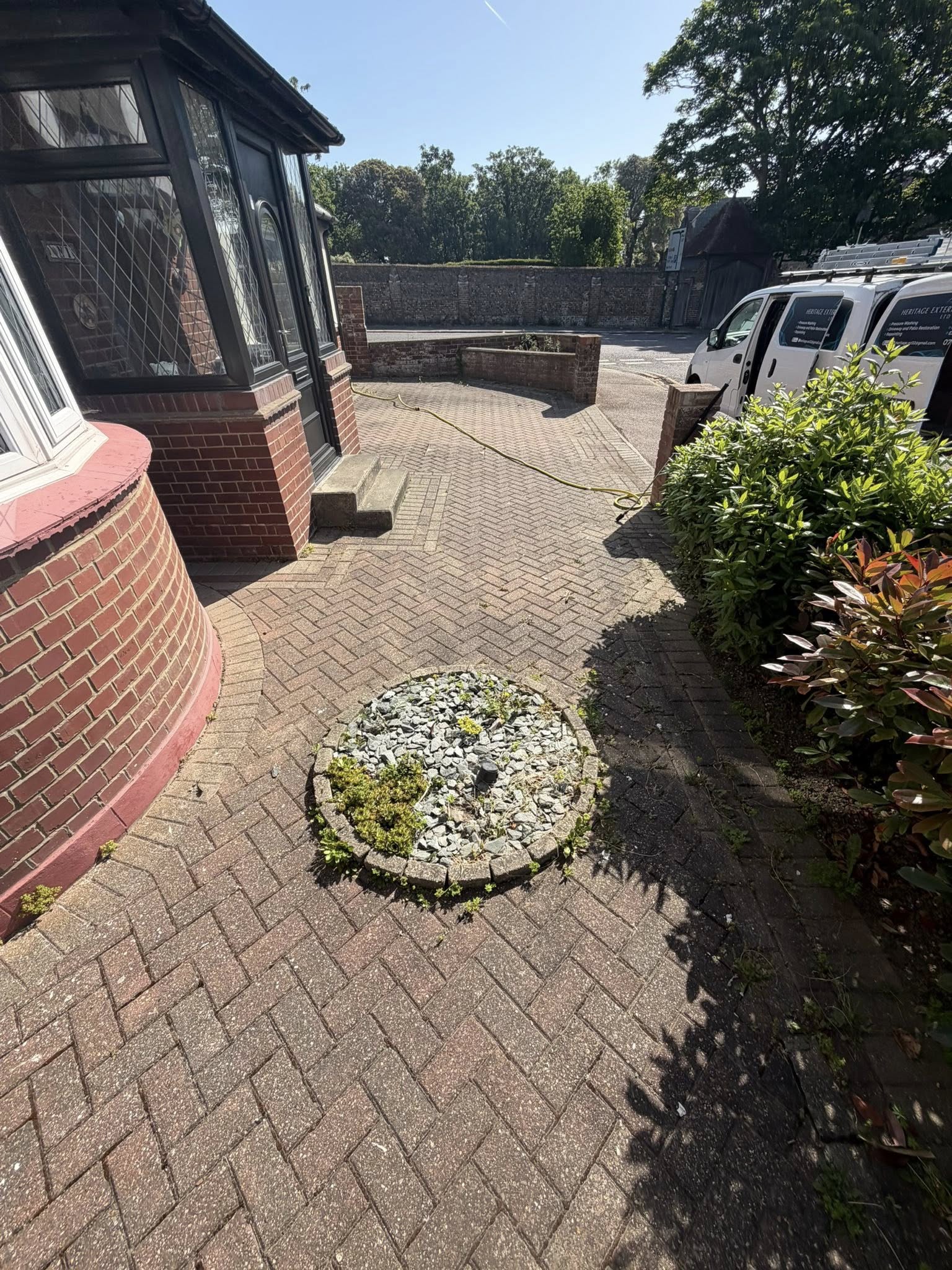 Paved driveway with decorative gravel planter and shrubs